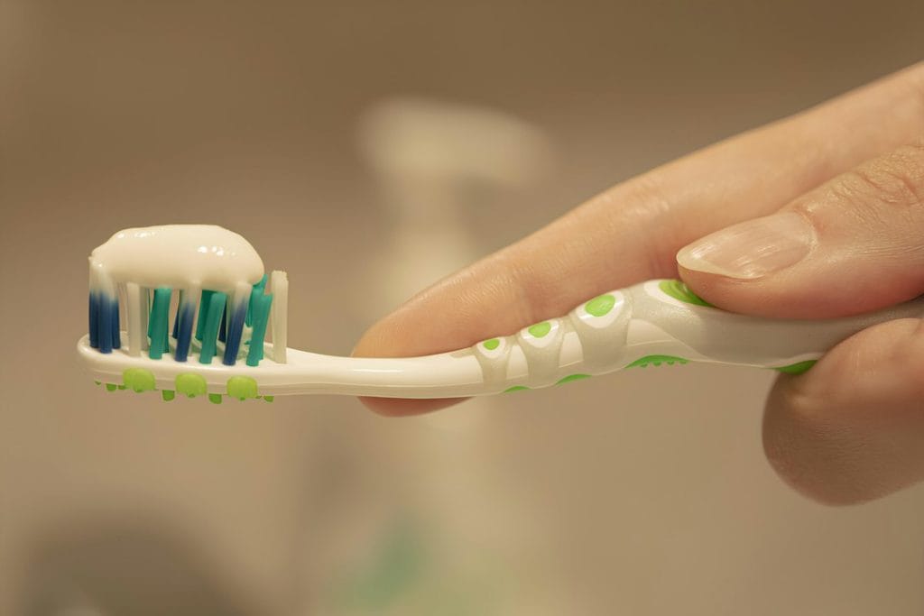 Person holding a soft toothbrush for gentle oral care after wisdom teeth removal