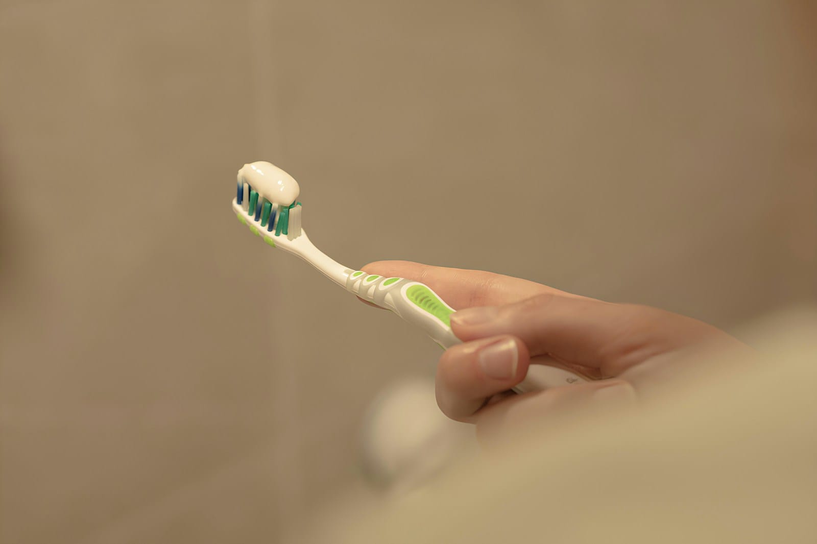 Close-up of a person holding a toothbrush for gentle oral care after wisdom teeth removal