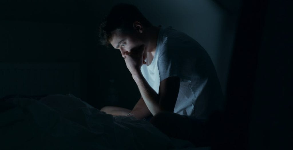 Adult holding their cheek while experiencing tooth pain at night